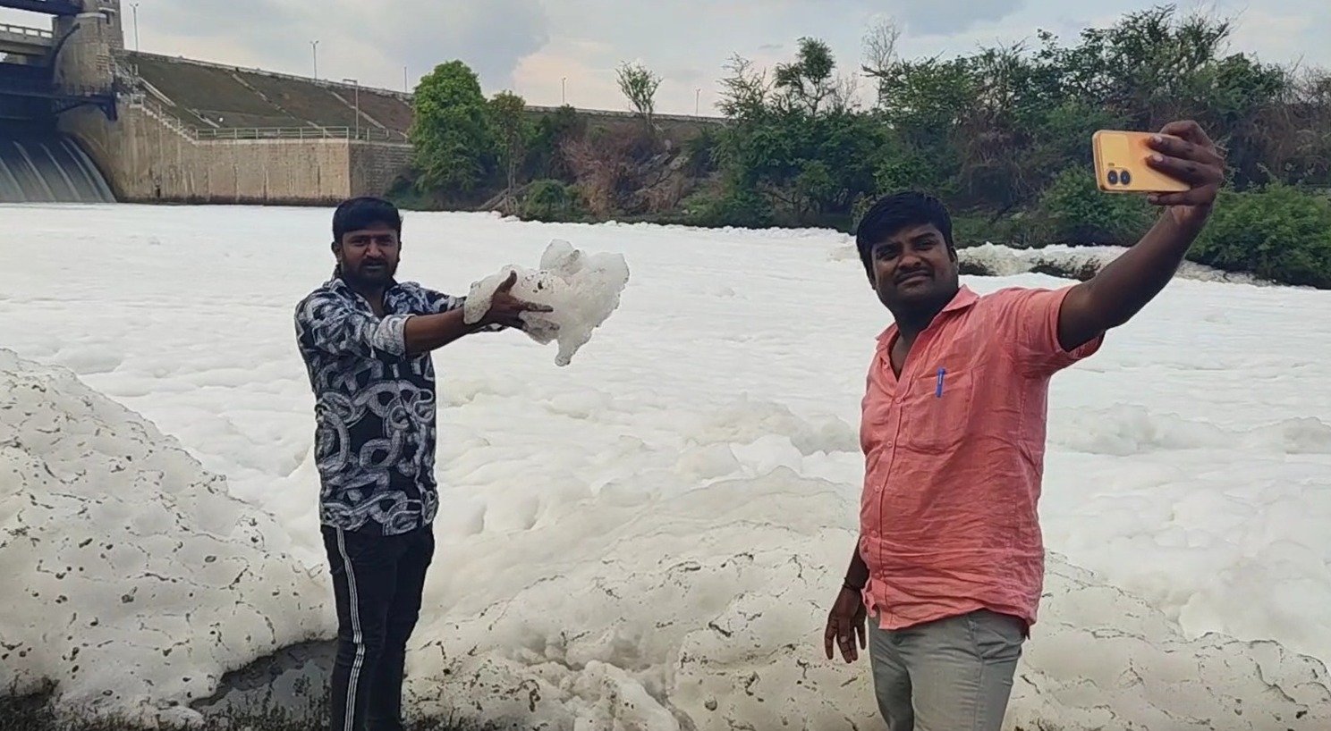 ஓசூர் அடுத்த கெலவரப்பள்ளி நீர்தேக்க அணையிலிருந்து தென்பெண்ணை ஆற்றில் வெளியேறும் நீரில் நான்காவது நாளாக குவியல் குவியலாக நுரை: தூர்நாற்றம் வீசும் நுரையில் விளையாடி செல்பி எடுக்கும் பொதுமக்கள்